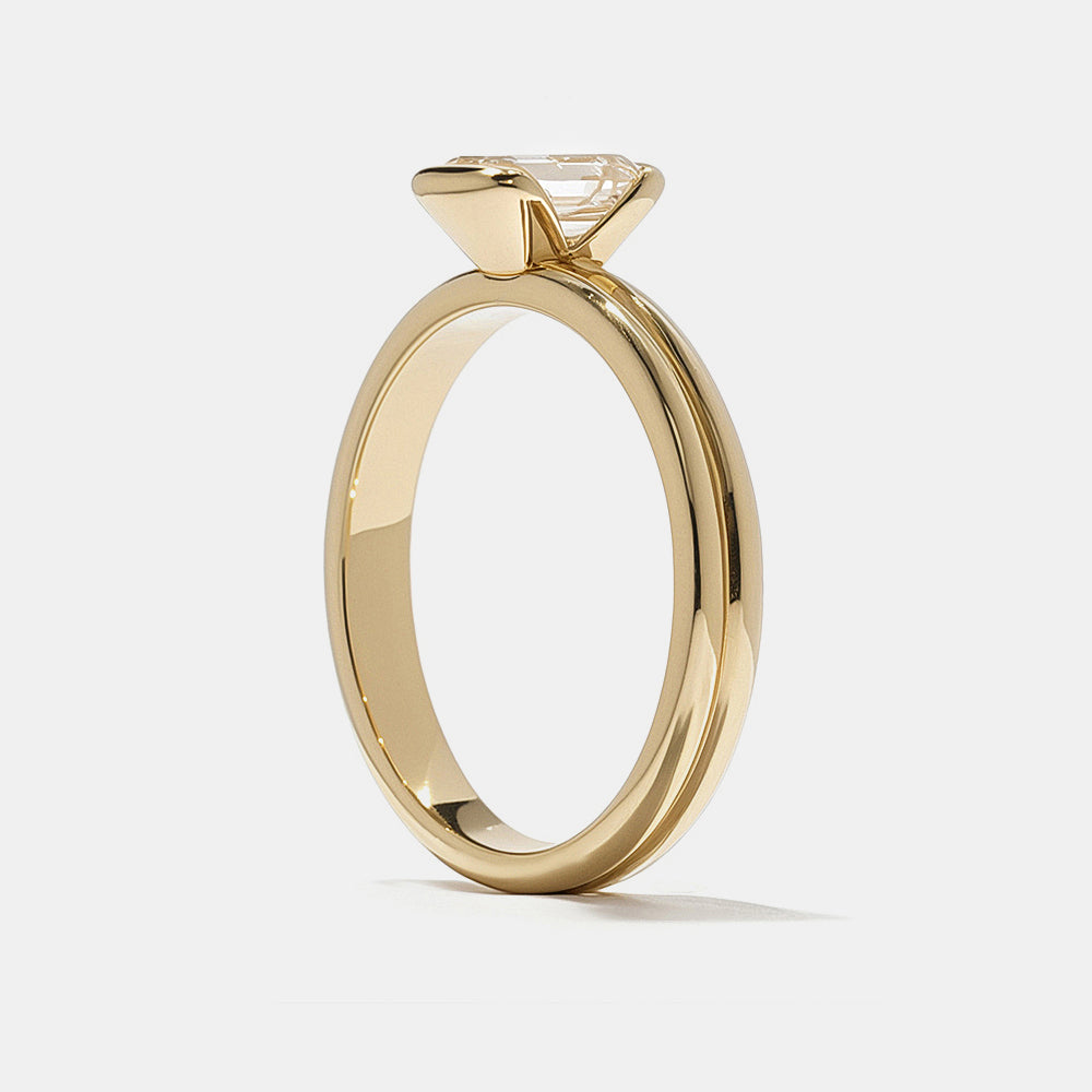 0.75 carat emerald cut E VS1 CVD lab grown diamond half bezel solitaire engagement ring in minimal modern gold setting