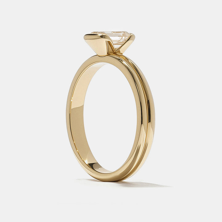 0.75 carat emerald cut E VS1 CVD lab grown diamond half bezel solitaire engagement ring in minimal modern gold setting