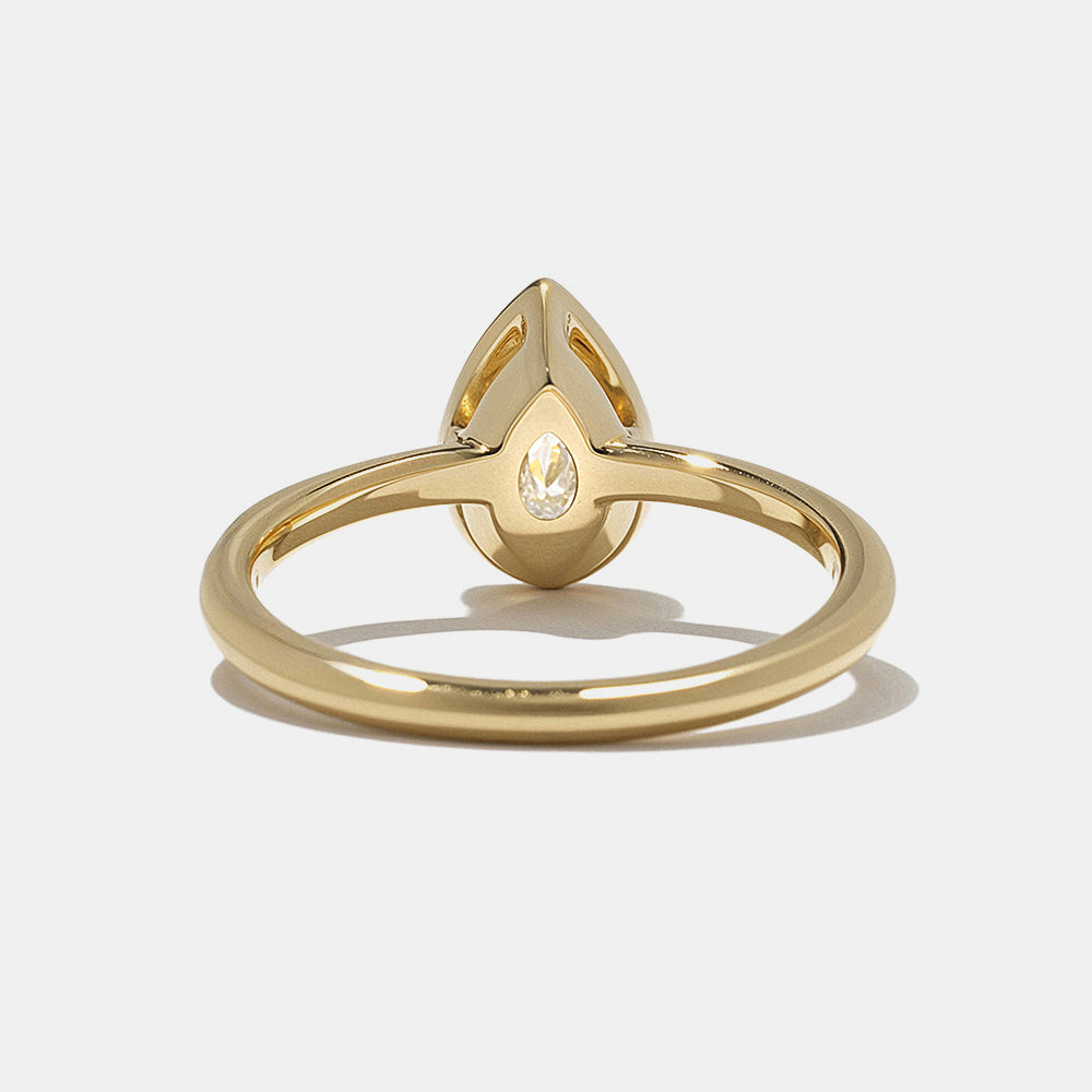 0.75 carat pear cut lab grown diamond bezel solitaire engagement ring in minimal gold band with clean modern style