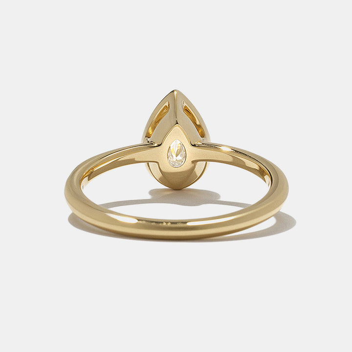 0.75 carat pear cut lab grown diamond bezel solitaire engagement ring in minimal gold band with clean modern style
