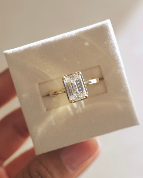 1.50 carat emerald cut lab grown diamond bezel solitaire engagement ring crafted in polished gold with contemporary elegance
