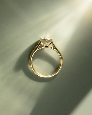 Pear cut lab diamond engagement ring featuring a cathedral setting and sleek bezel frame around the center stone