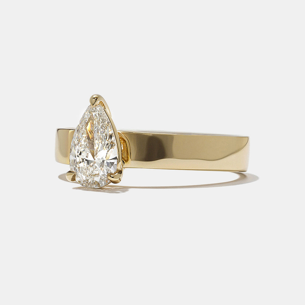 Side profile of pear cut lab diamond cigar band solitaire engagement ring highlighting bold band and secure setting