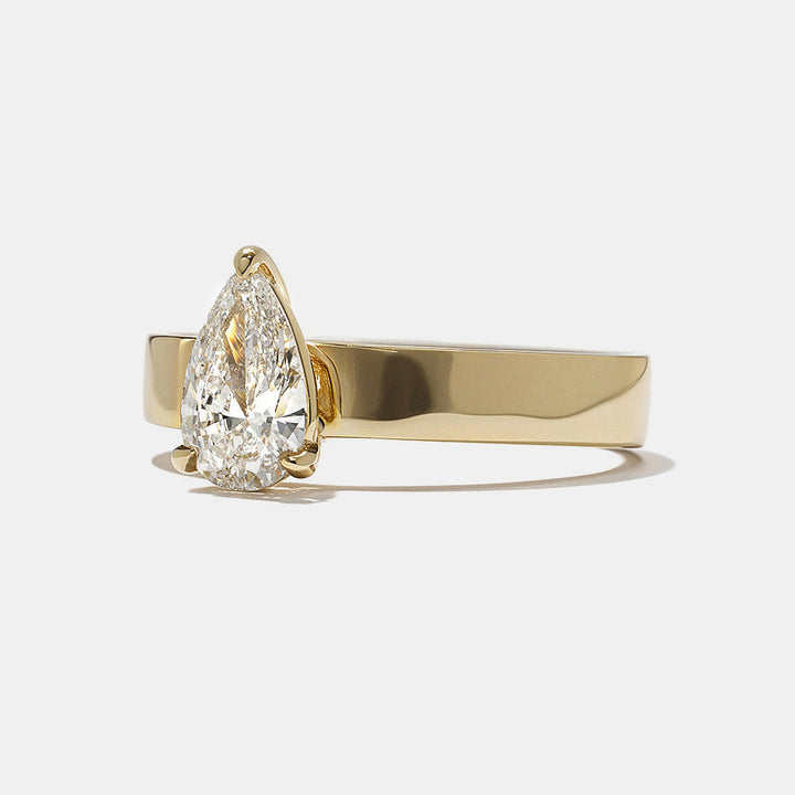 Side profile of pear cut lab diamond cigar band solitaire engagement ring highlighting bold band and secure setting