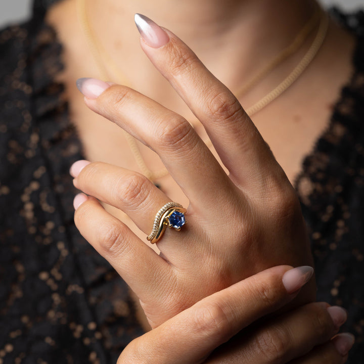 Lifestyle image of a 1.5 carat hexagon blue sapphire engagement ring with lab diamond curved band elegance