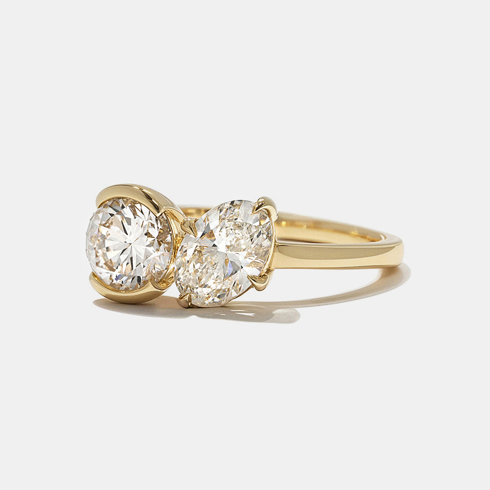 Contemporary engagement ring featuring round and oval lab grown diamonds in bezel Toi Et Moi design with modern clean lines