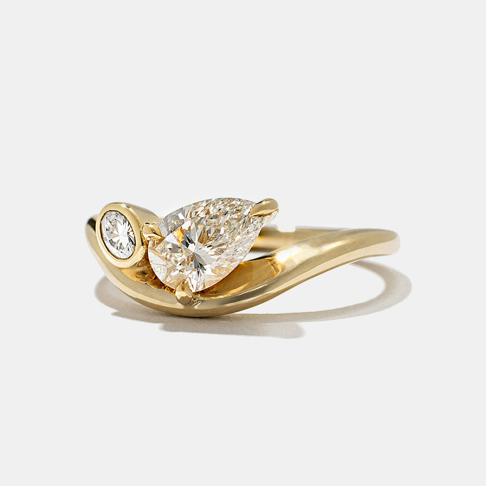 Detailed view of pear and oval lab diamond bezel Toi Et Moi engagement ring highlighting contrast and clean styling