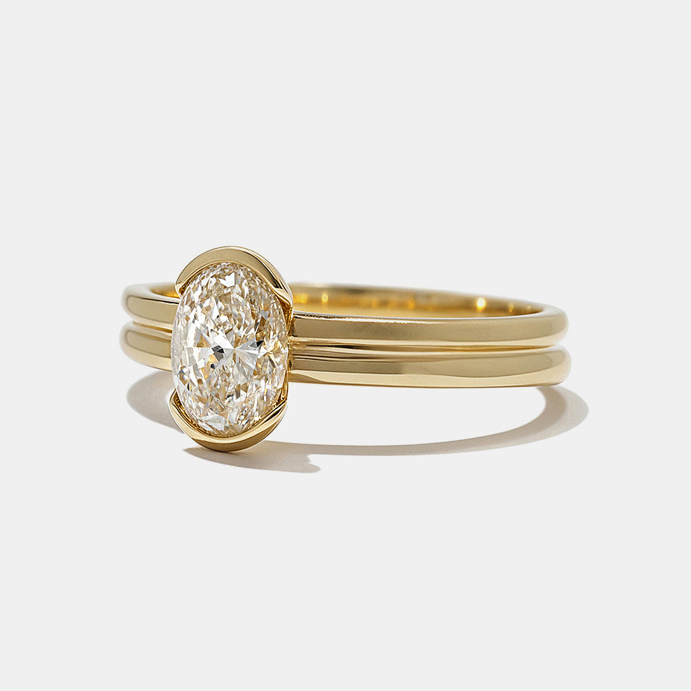 Close-up of oval lab grown diamond half bezel engagement ring showing partial bezel and open modern setting design