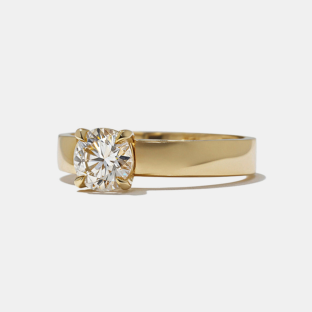 Close-up of round lab grown diamond cigar band engagement ring showing bold wide band and secure solitaire setting
