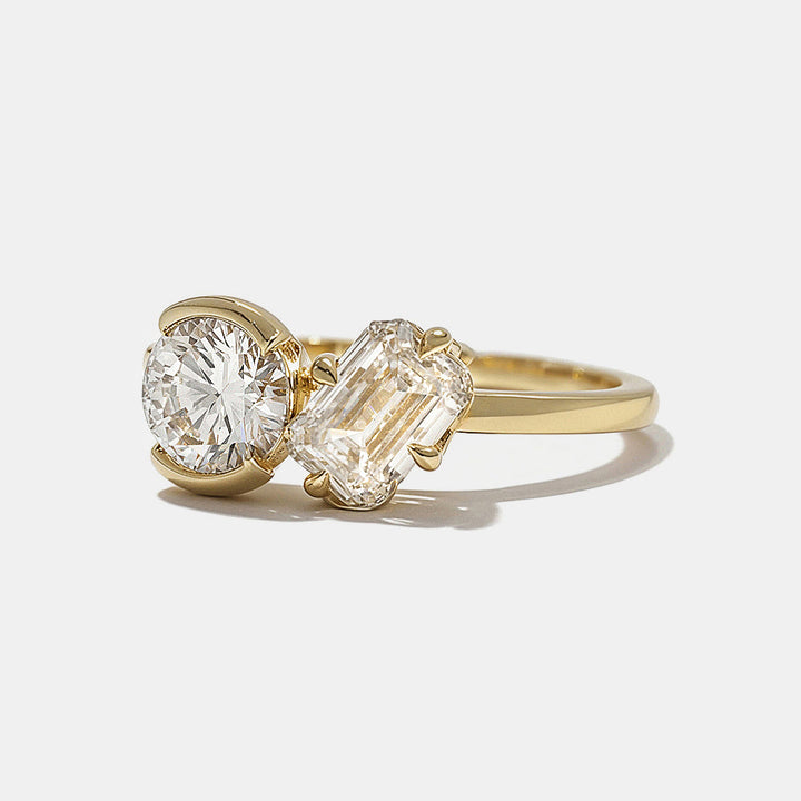 Close-up of round and emerald cut lab diamond Toi Et Moi engagement ring showing smooth bezel set dual stone design