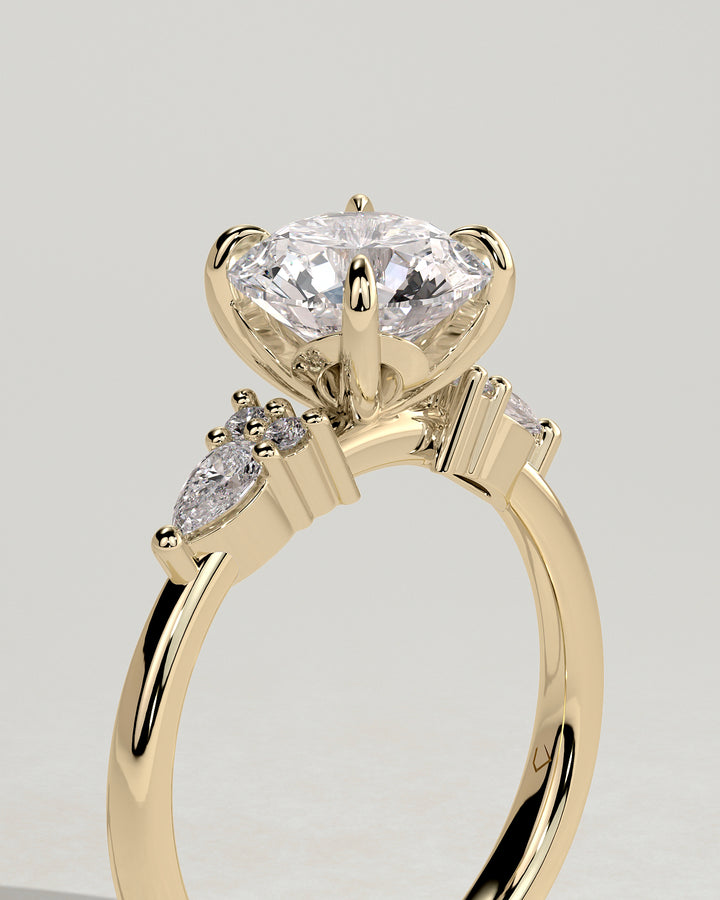 Round diamond ring with pear side stones and paved shoulder